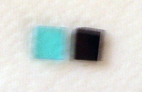A blurry photograph showing the colors of the factory IR filter, transparent blue to left, and the aftermarket visible light filter, opaque black to right.