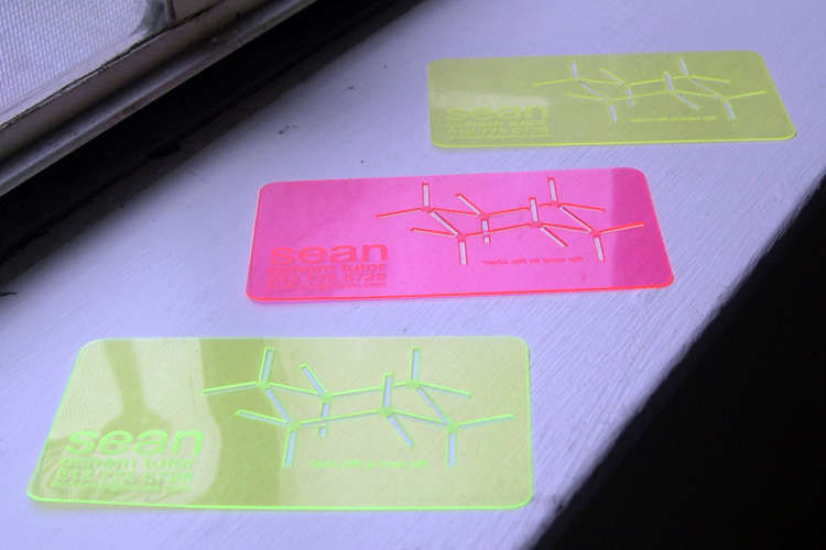 Combination business cards and drawing templates in three fluorescent colors, arrayed on a windowsill.