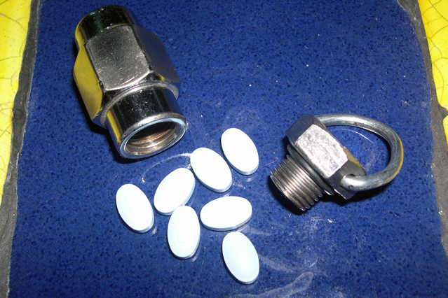 Lug nut pill case, with D-ring, open, showing o-ring seal and charge of 7 generic naproxen.  The case holds a surprisingly large amount.