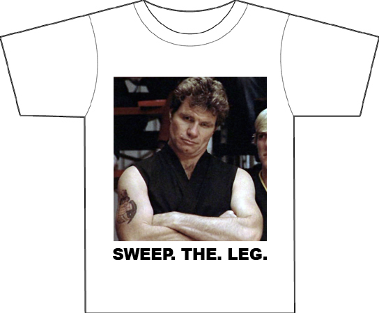 A white T-shirt with an image of evil sensai John Kreese from 'The Karate Kid' and text reading 'SWEEP. THE. LEG.'